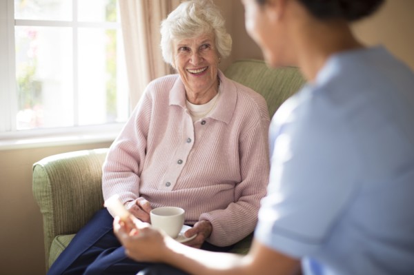 Nurse and patient drinking tea on sofa