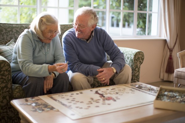 Older couple on sofa solving jigsaw puzzle