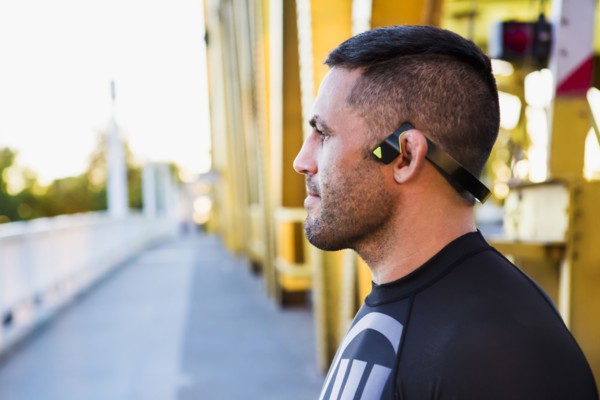 Pensive Caucasian man wearing modern headphones on bridge
