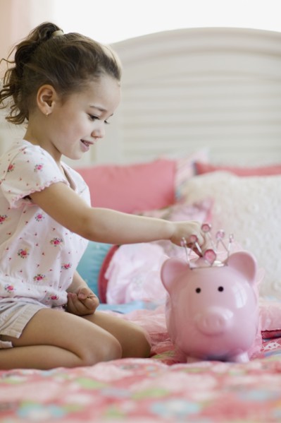 Young girl putting money in piggy bank