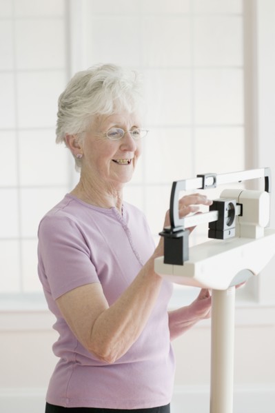Senior woman weighing self on scale