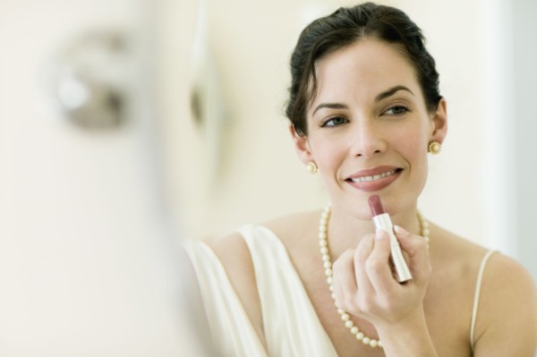Woman in fancy clothing applying lipstick