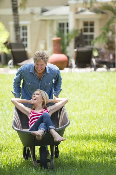 Caucasian man pushing girlfriend in wheelbarrow