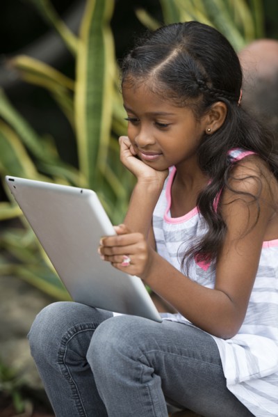 Mixed race girl using digital tablet outdoors