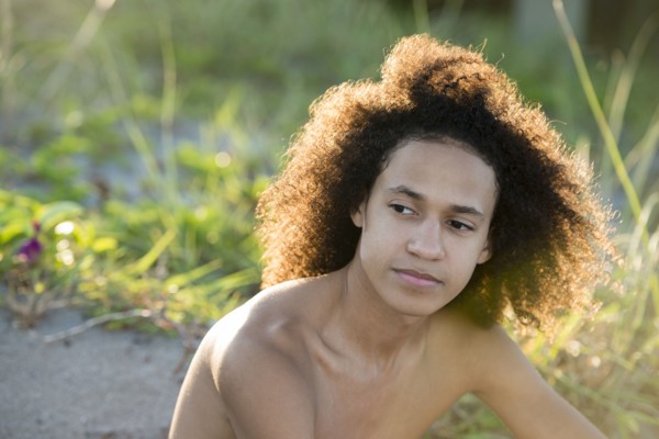 Mixed race teenage boy sitting on beach