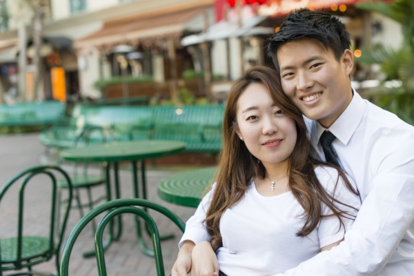 Korean couple hugging at sidewalk cafe