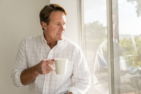Caucasian man drinking cup of coffee near window