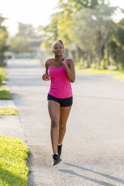 Mixed race woman jogging on suburban sidewalk