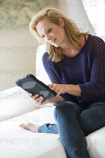 Caucasian woman using digital tablet on sofa