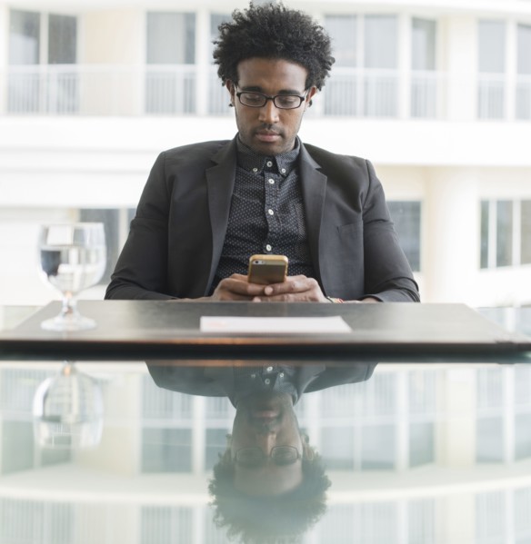 Hispanic businessman using cell phone at conference table