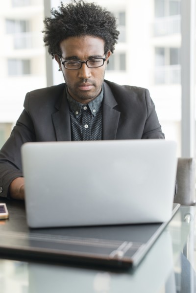 Hispanic businessman using laptop in office