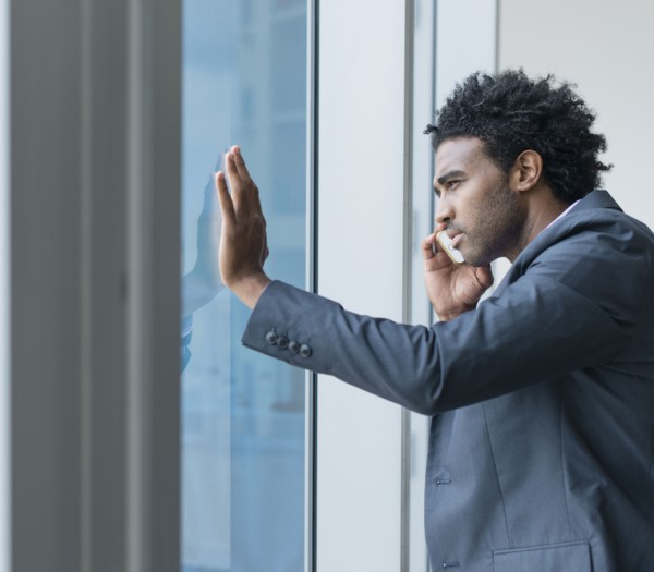 Hispanic businessman talking on cell phone at office window