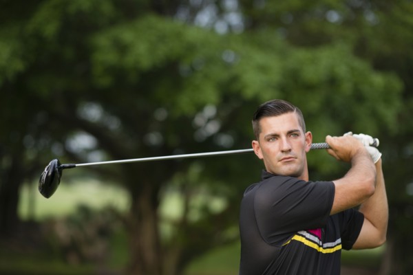 Caucasian man swinging club on golf course