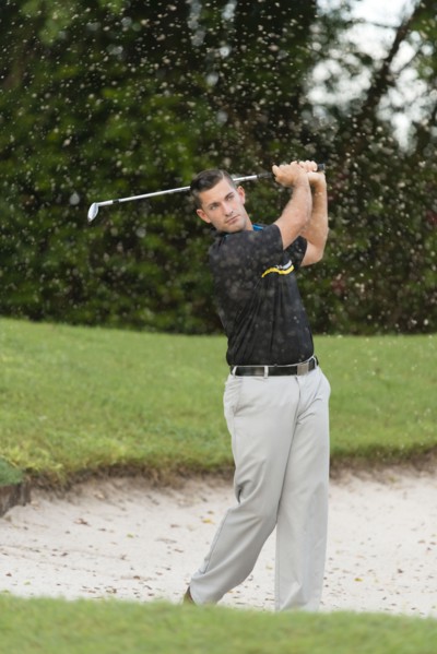 Caucasian man chipping from golf course sand trap