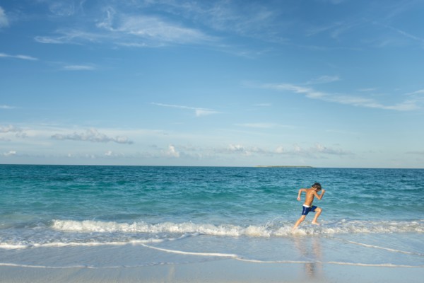 Hispanic boy running on beach