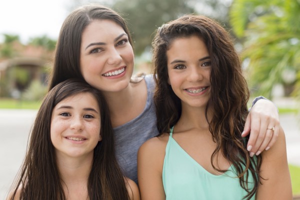 Mother and daughters smiling outdoors