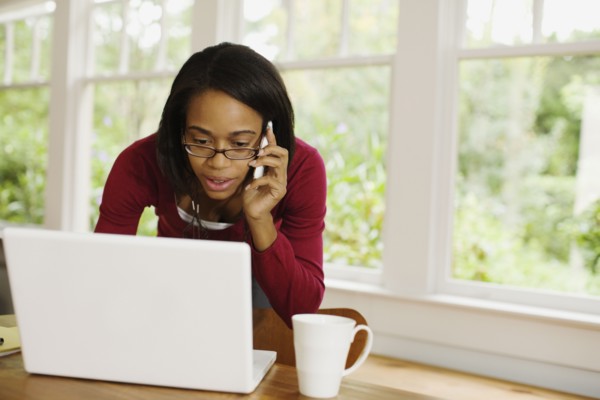 African woman talking on cell phone and using laptop