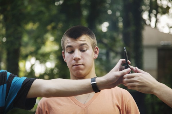 Teenager watching friends exchange cell phone