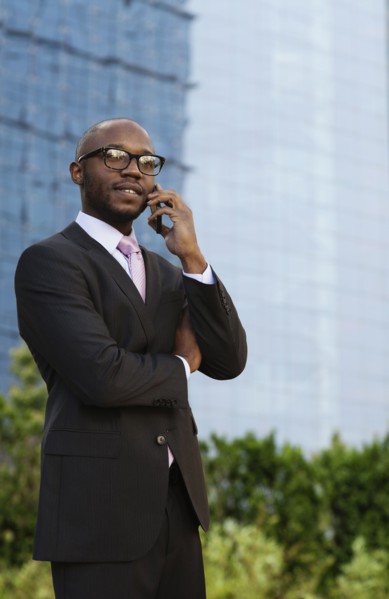 Black businessman talking on cell phone on city street