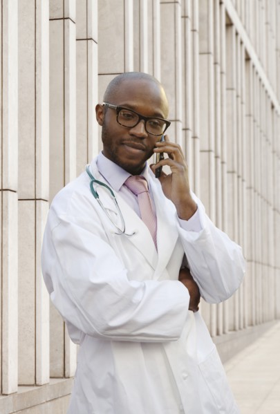 Black doctor talking on cell phone on city street