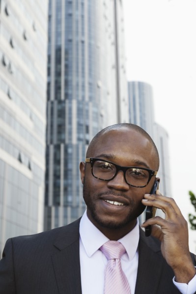 Black businessman talking on cell phone on city street