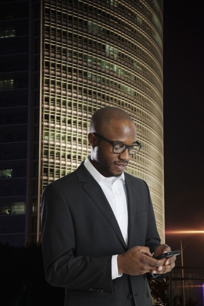 Black businessman using cell phone on city street