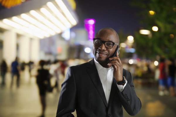 Black businessman talking on cell phone on city street
