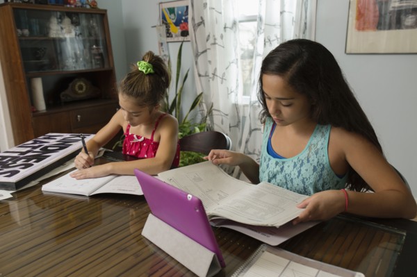 Mixed race sisters doing homework at table
