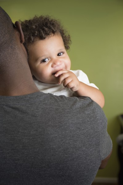 Father holding toddler son in bedroom