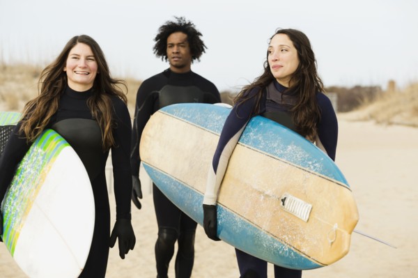 Surfers carrying boards on beach