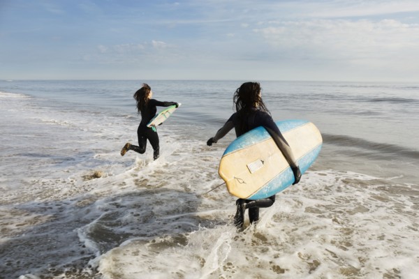 Surfers carrying boards in waves