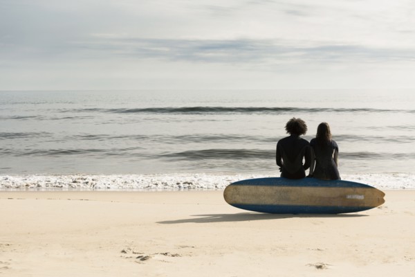 Surfers sitting on board on beach