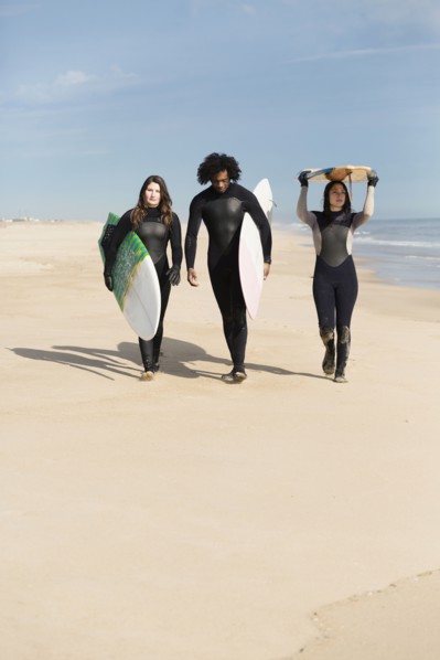 Surfers carrying boards on beach