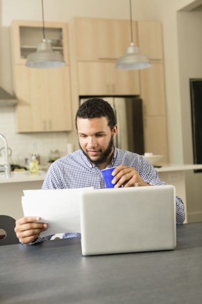 Mixed race man reading at breakfast table