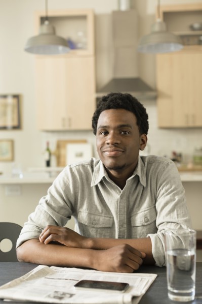 Black man reading newspaper at breakfast table