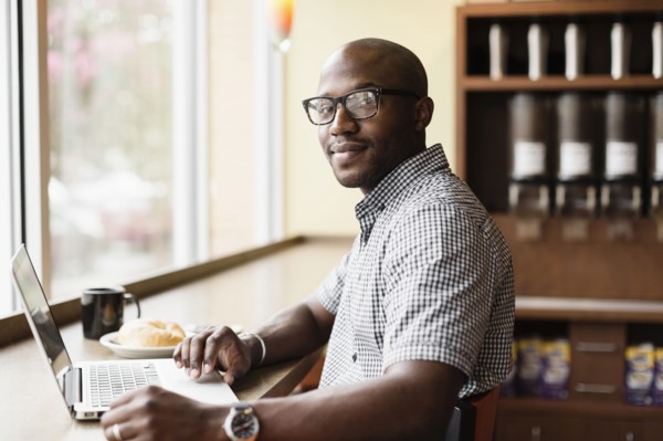 Black man using laptop in coffee shop