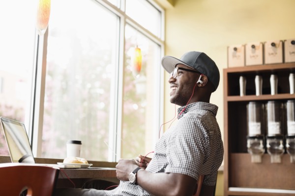 Laughing Black man using laptop in coffee shop