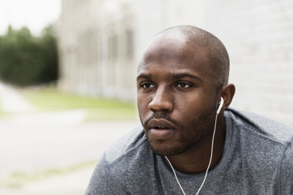 Black runner resting in city with earbuds