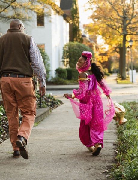 African American girl trick-or-treating with father on Halloween