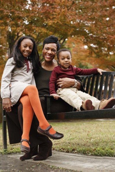 African American mother and children sitting on park bench