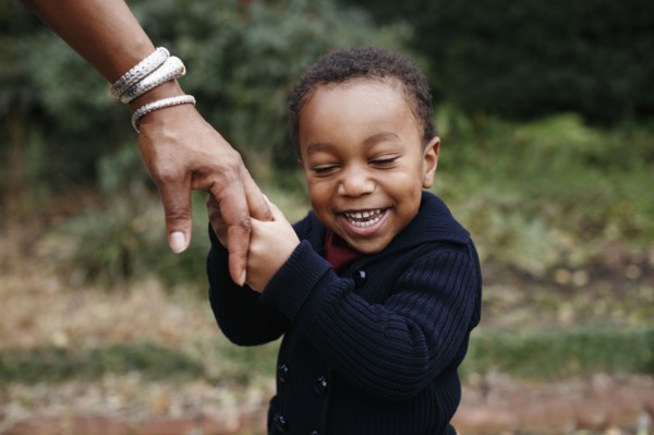 African American boy holding hand of mother in park