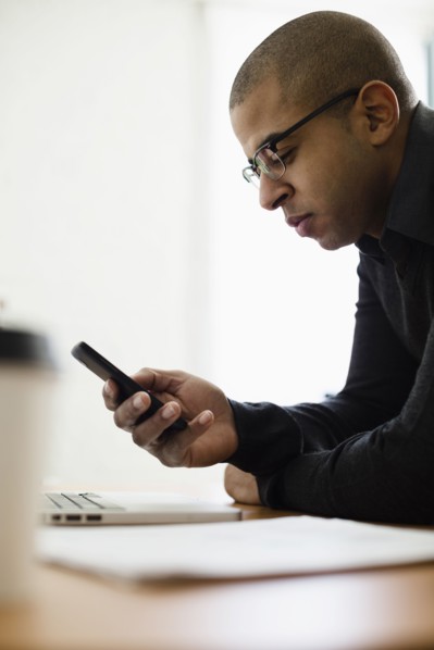 Mixed race businessman using cell phone at desk