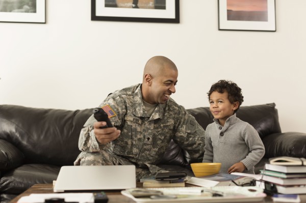 Mixed race soldier father and son watching television in living room