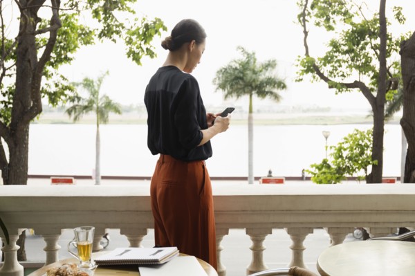 Asian businesswoman using cell phone on balcony
