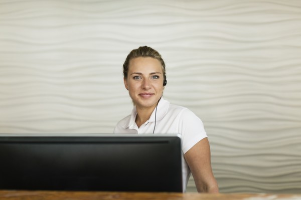 Caucasian concierge smiling behind hotel front desk