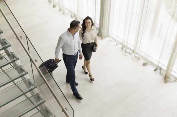 High angle view of business people rolling luggage in hotel lobby