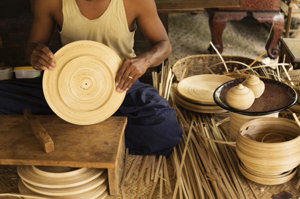 Asian artisan weaving traditional baskets in workshop