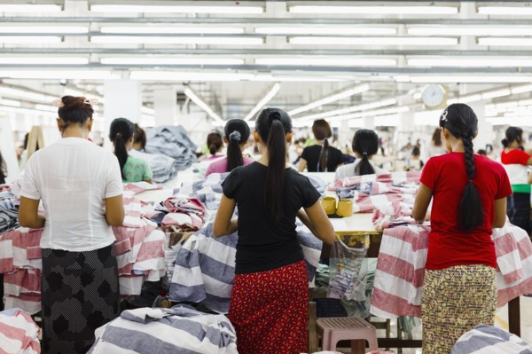 Asian workers sewing clothing in garment factory