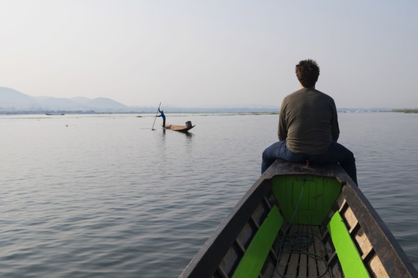 Caucasian man sitting on canoe on rural lake
