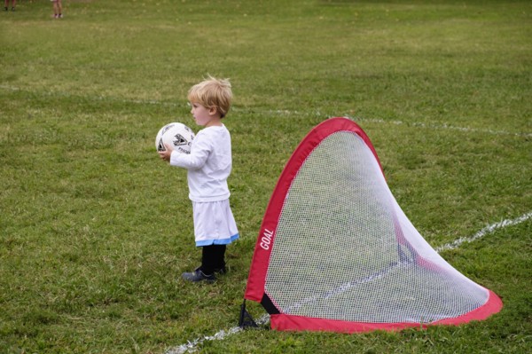 Caucasian boy playing soccer in field